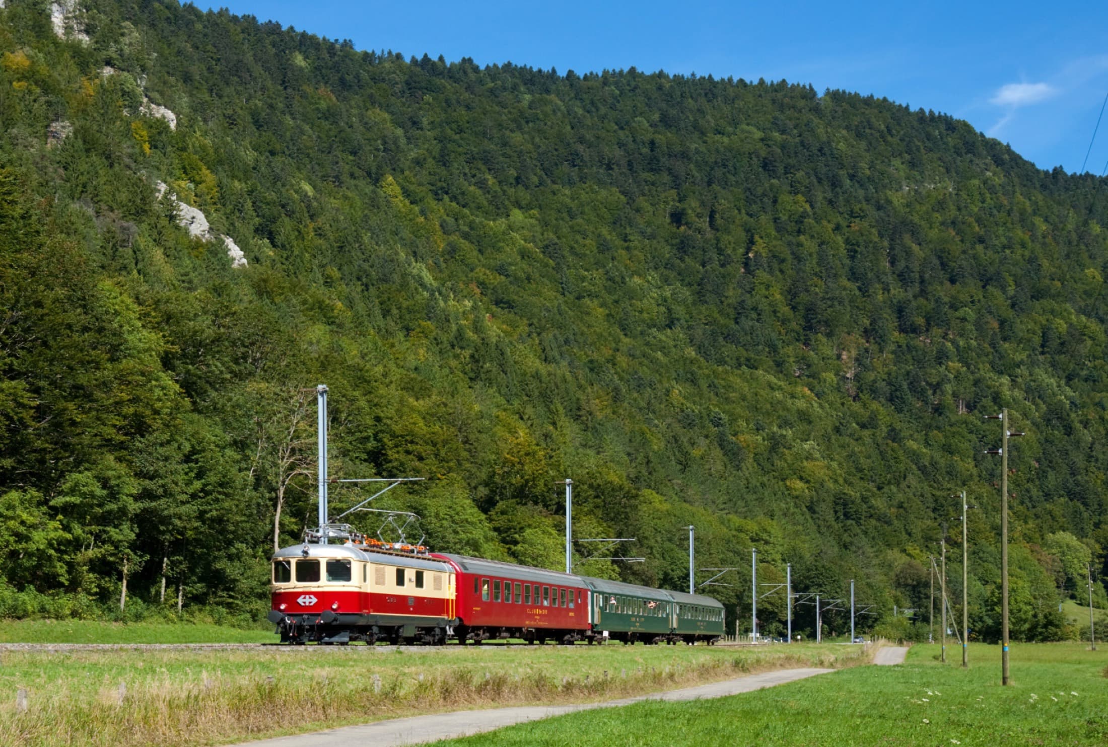 Historischer Schnellzug mit rot-cremefarbenem Triebwagen im Tal